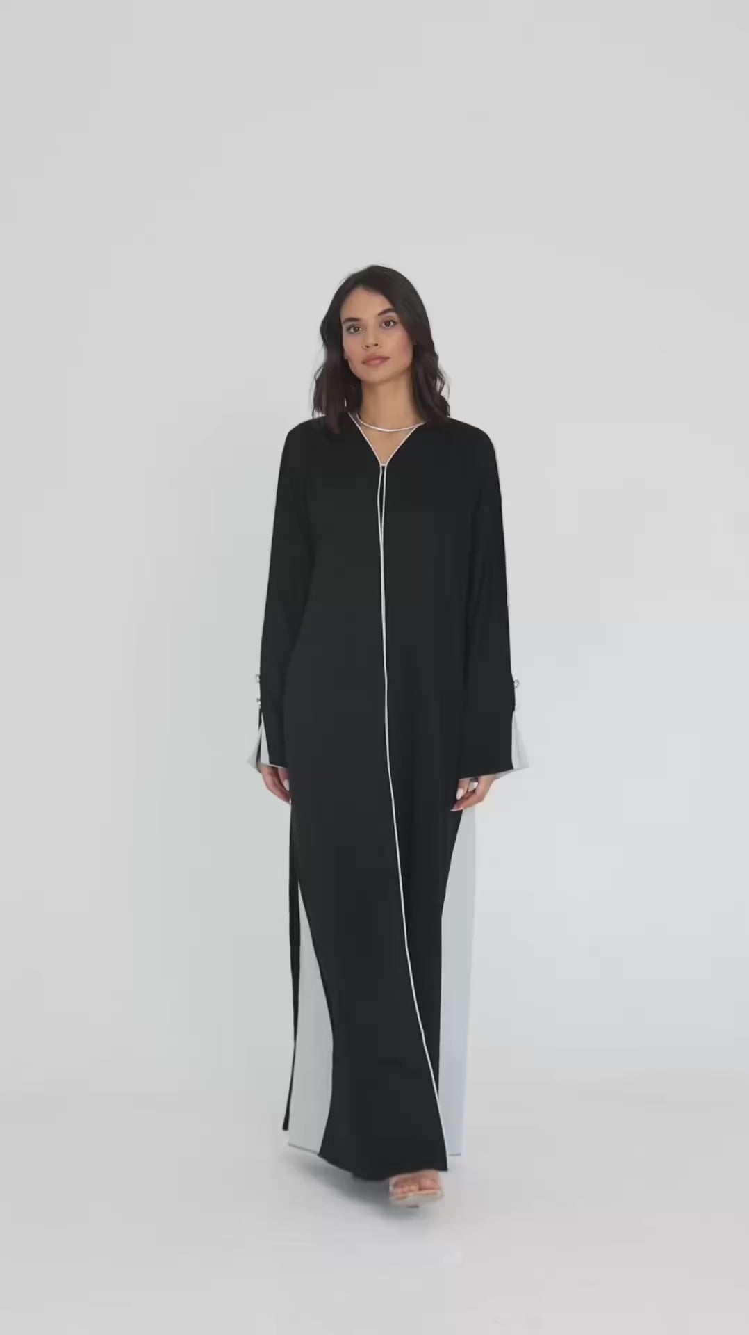 Video of a female model doing a catwalk in a gray white abaya