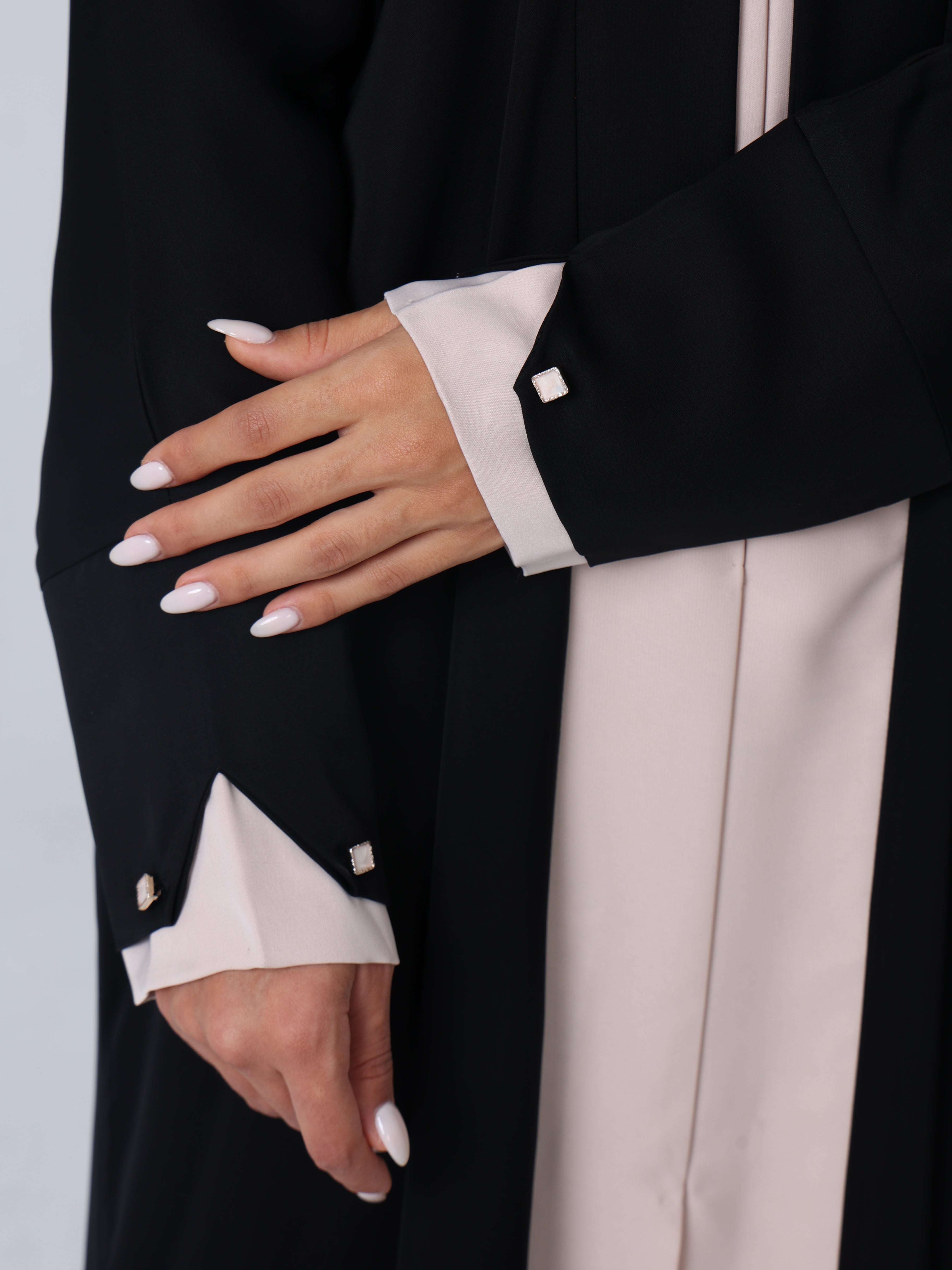 Close-up of black RUMI abaya cuff with beige lining and square beige buttons