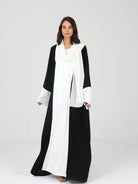 Model walking in black and white RUMI abaya, styled with a white scarf and soft drape