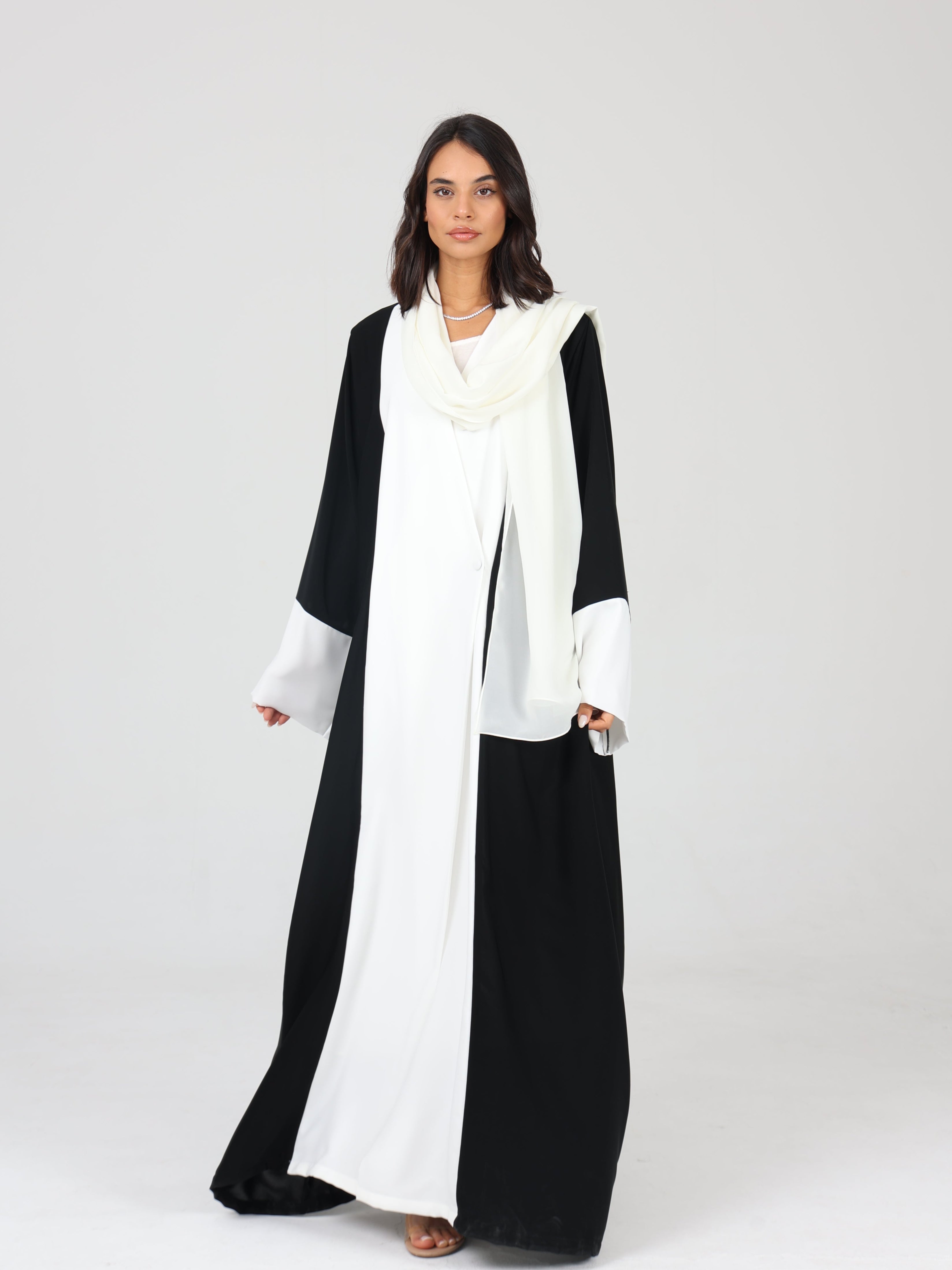 Model walking in black and white RUMI abaya, styled with a white scarf and soft drape