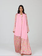 Model walking forward in RUMI pink floral abaya with soft chiffon scarf and relaxed silhouette