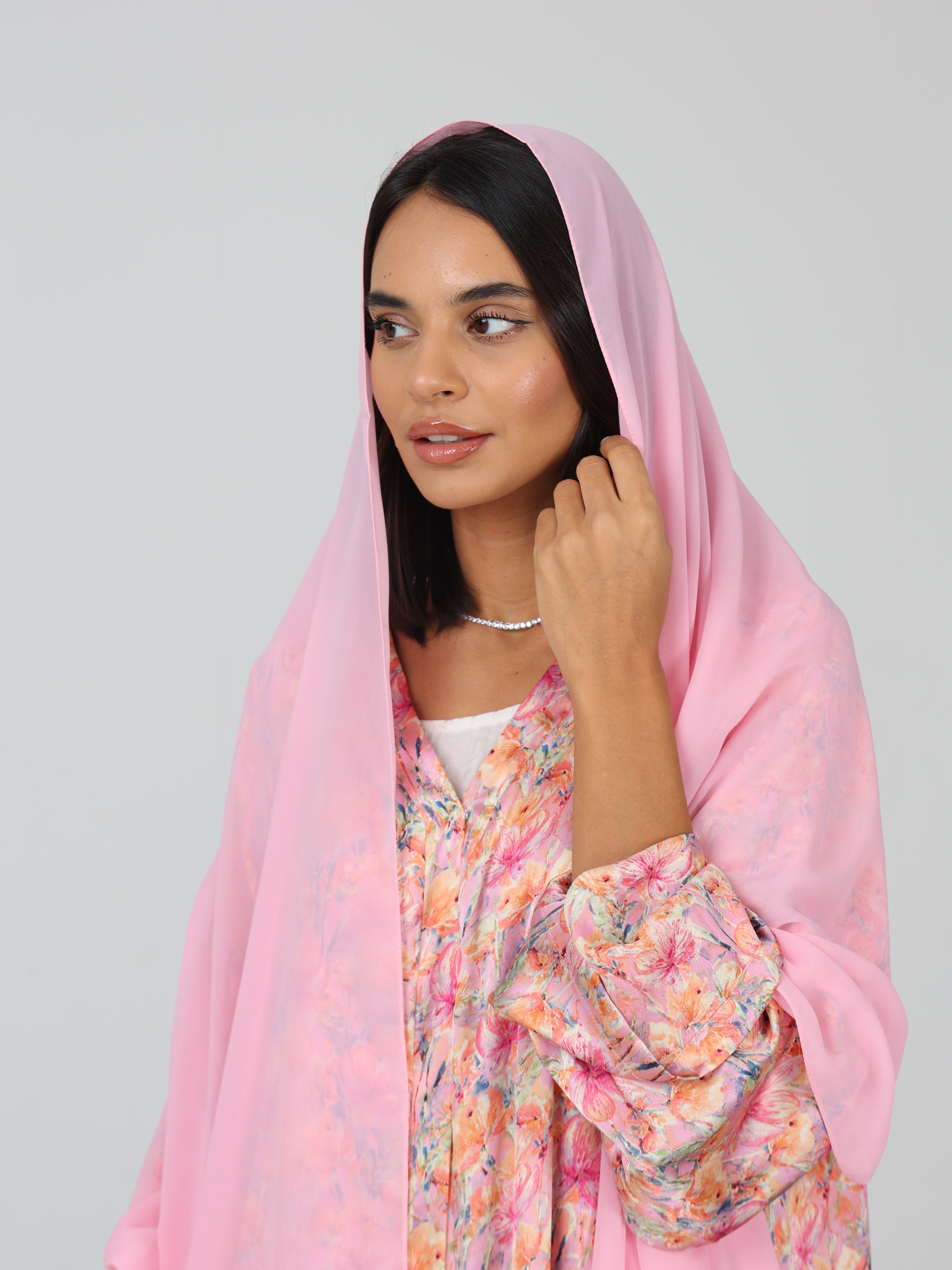Close-up of model in pink silk floral abaya with matching pink chiffon sheila draped over her head