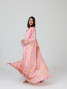 Model in RUMI pink floral abaya mid-turn, showing the fabric’s flow and full print in motion
